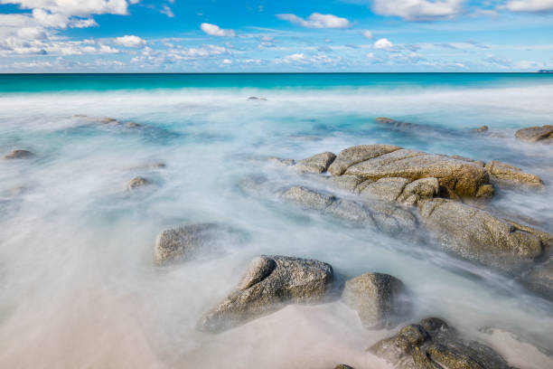 istock Clean ocean waves flowing over rocks on the beach 1301505013