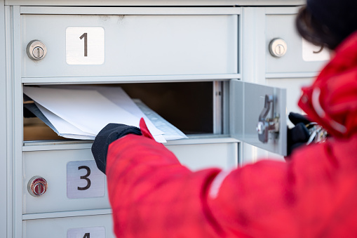 Woman Wearing Gloves Picking up the Mail at Postal Mailbox During Winter Season