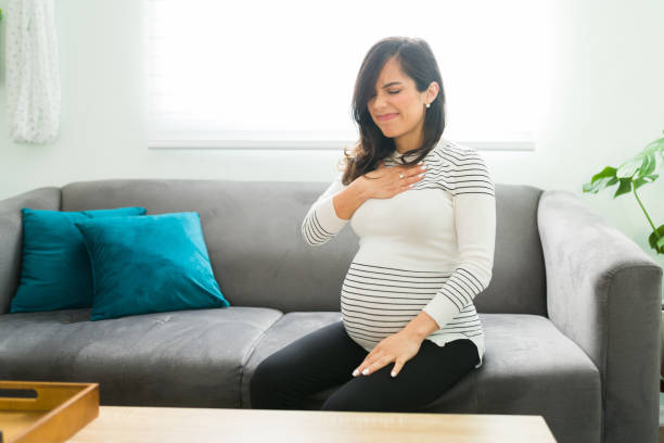 schwangere frau mit säureigen reflux wegen ihrer schwangerschaft - refluxkrankheit stock-fotos und bilder