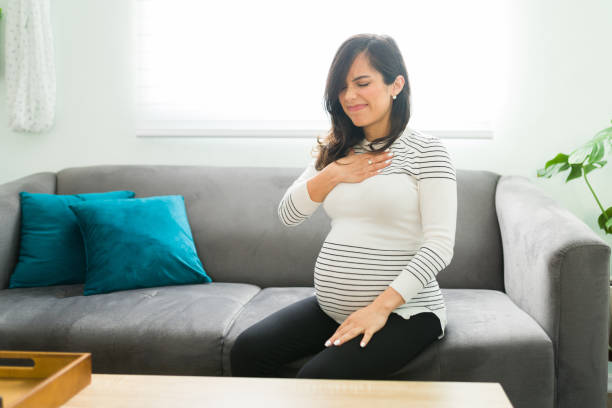 Pregnant wife having acid reflux because of her pregnancy Pretty pregnant woman suffering from acid reflux because of her pregnancy. Caucasian expectant mother touching her chest with a pained expression gastroesophageal reflux disease photos stock pictures, royalty-free photos & images