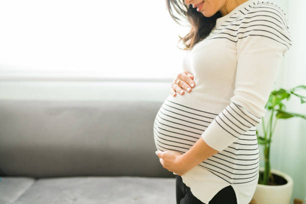 istock Adorable expectant mother showing her round belly 1301510593