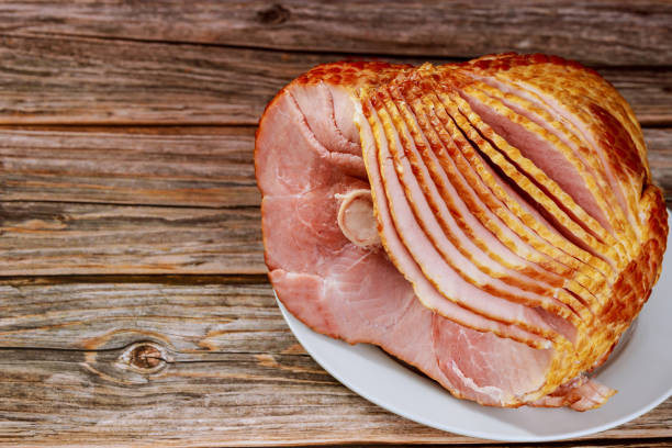 istock Hickory smoked spiral sliced ham on wooden background. 1301516669