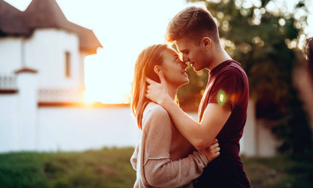 istock Charming couple kissing with a white building on background posing during a summer sunset traveling 1301517700
