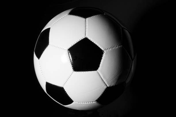 istock Black and white soccer ball on black background 1301522549