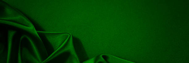 istock Black green silk satin background. Copy space for text or product. Wavy soft folds on shiny fabric. 1301523049