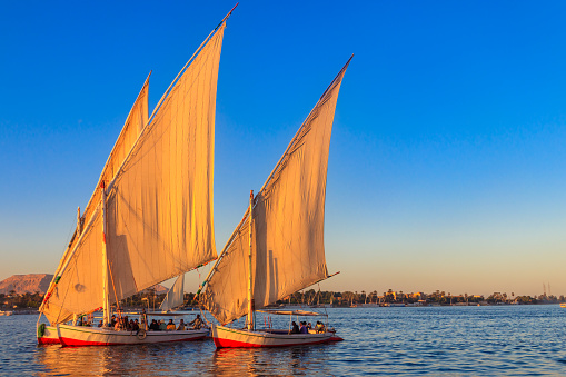 Luxor, Egypt - December 11, 2018: Felucca boats sailing on the Nile river in Luxor, Egypt. Traditional Egyptian sailing boats