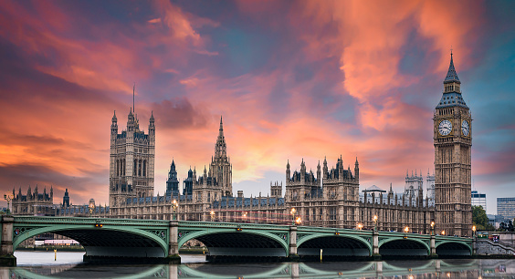 Stunning sunset over London's southern part with Westminster Abbey, Big Ben, Houses of Parliament, Westminster bridge and the Thames river flowing in the foreground.
