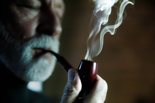 Close up of a senior man smoking a pipe. Copy space.