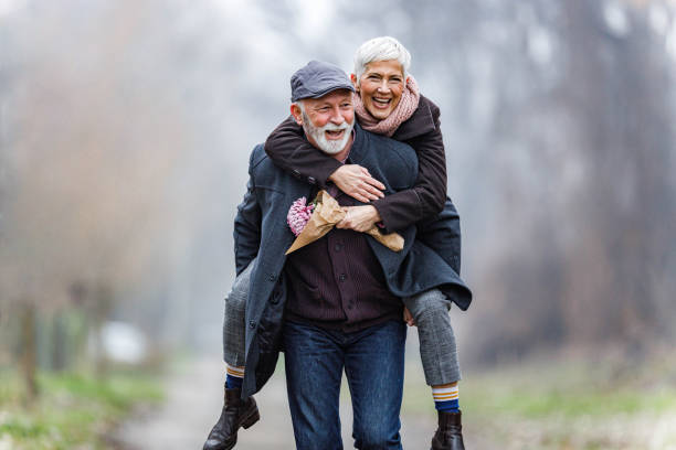 figlarna dojrzała para piggybacking w zimowy dzień. - senior adult retirement mature adult couple zdjęcia i obrazy z banku zdjęć