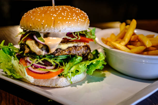 istock Fresh juicy burger with fried potatoes on a white plate in a cafe. 1301530342