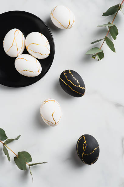 istock Modern style Easter eggs decorated with golden metal on marble background. Flat lay, top view, vertical 1301530379