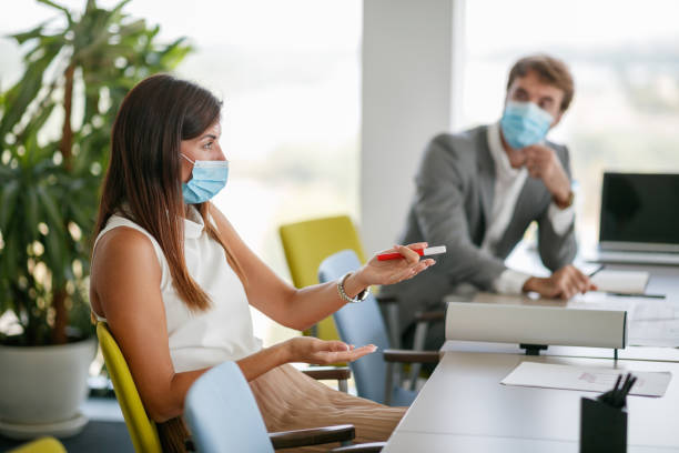 istock Beautiful businesswoman with protective face mask  analyzing situation and gesturing in a meeting 1301531673