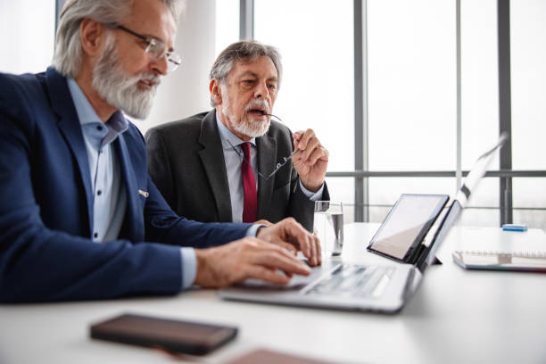 istock Two Mature Adult Corporate Businessmen Working On Processing Data With The Help Of Computers 1301532851