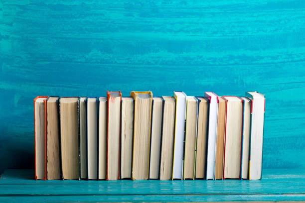 istock Books on bookshelf in Library. Back to School education concept on colored abstract blue background. Open hardback book stack in a raw on wooden desk table. 1301533149