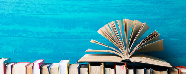istock Books on bookshelf in Library. Back to School education concept on colored abstract blue background. Open hardback book stack in a raw on wooden desk table. 1301534291