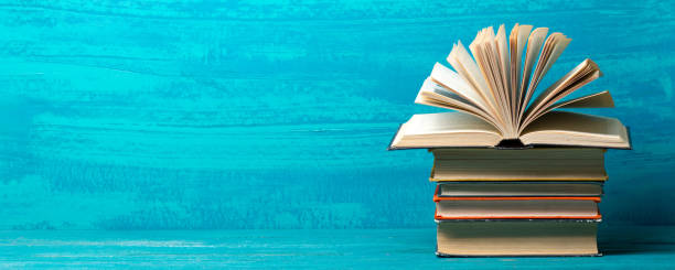 istock Books on bookshelf in Library. Back to School education concept on colored abstract blue background. Open hardback book stack in a raw on wooden desk table. 1301534338
