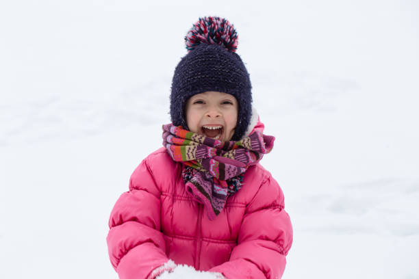 istock Warmly dressed little girl playing with snow close up. 1301535765