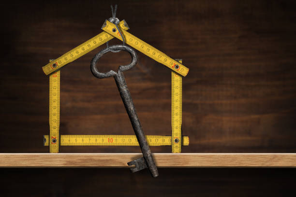 istock Folding Ruler House Shaped With an Old Key on a Wooden Shelf 1301537068