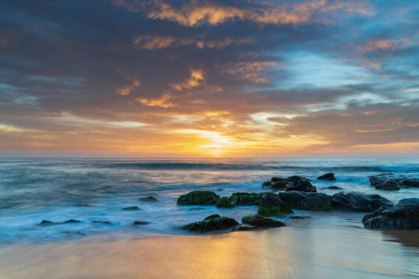 High clouds over the sea, blue, pink and orange sunrise from Killcare Beach on the Central Coast, NSW, Australia.