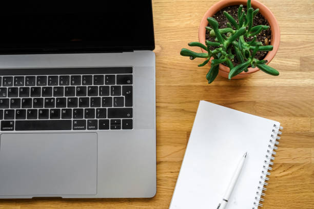 istock Office workplace with a laptop and notepad on a wooden table. Space for text 1301539898