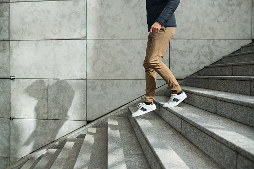 Young skate woman carrying longboard and walking up the stairs in the city