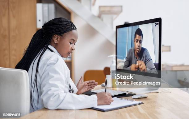 Taking Notes During Her Virtual Consult Stock Photo - Download Image Now - Telemedicine, Doctor, Patient
