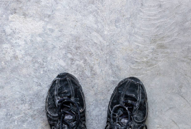 istock Dark old shoes on a white sand 1301544377