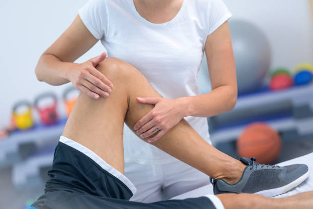 istock Female physiotherapist massaging patient's knee 1301545858