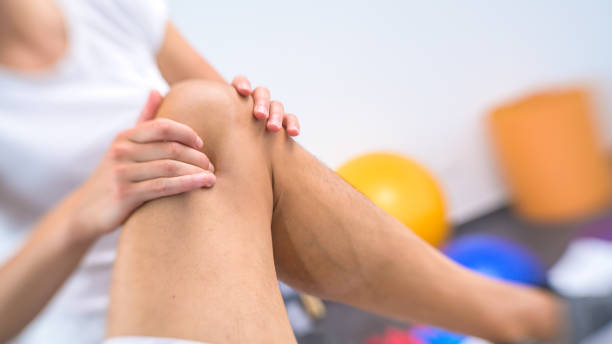istock Female physiotherapist massaging patient's knee 1301546619