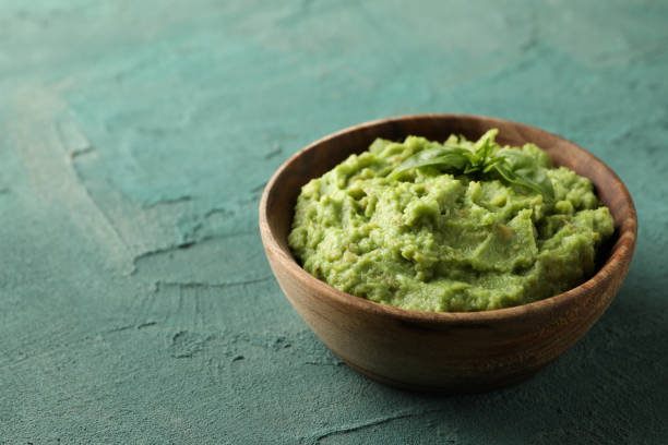 istock Bowl of guacamole on green textured background, space for text 1301546759