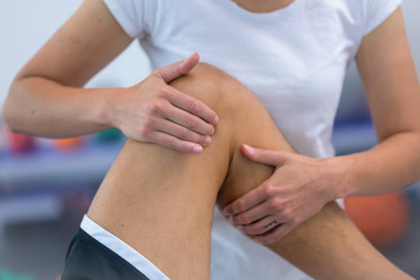 istock Female physiotherapist massaging patient's knee 1301546789