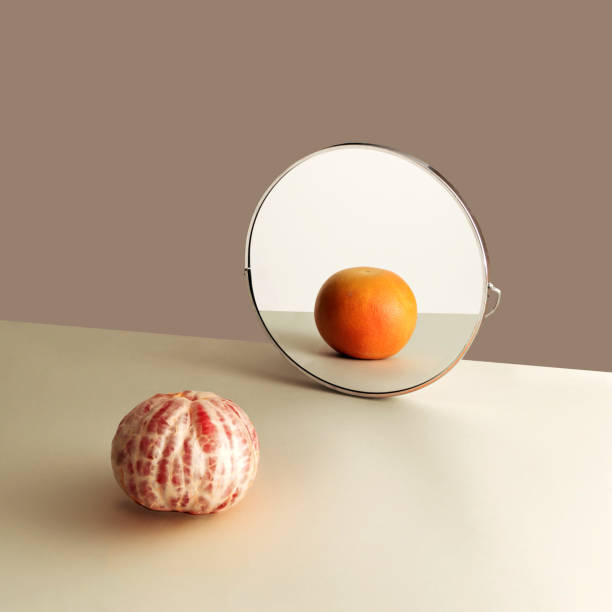 istock Mirror reflection of grapefruit peeled one opposite whole fruit. Beige color domination in the background. 1301546905