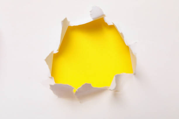 istock Hole in paper on yellow background, space for text 1301548562
