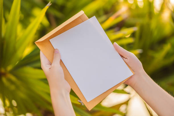 istock Women's hands in a tropical background holding a signboard paper, mockup 1301549263