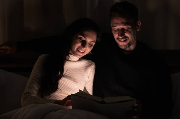istock Couple lover sitting on bed and reading book at night time 1301550261