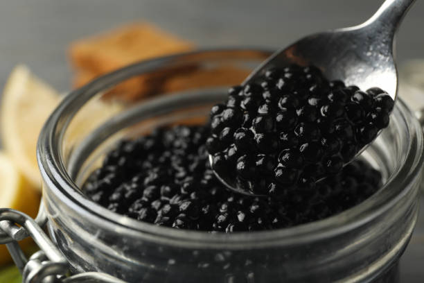 istock Glass jar and spoon with black caviar, close up 1301550307