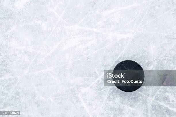 Black Old Rubber Puck On Ice Background Closeup Empty Place For Text Top Down View Stock Photo - Download Image Now