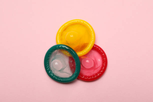 istock Multicolored condoms on pink background, close up 1301552902