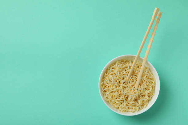 istock Bowl with noodles and chopsticks on mint background 1301553328