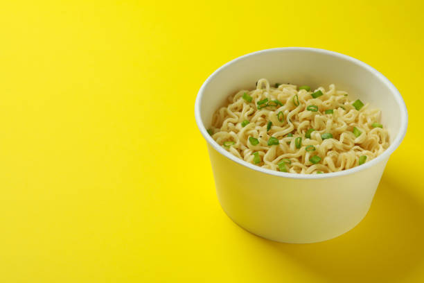 istock Cooked instant noodles in paper cup on yellow background 1301553675