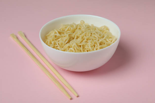 istock Bowl with noodles and chopsticks on pink background 1301554354