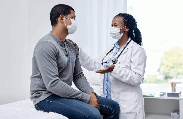 Offering patient-centred care that proves effective and efficient Shot of a doctor having a consultation with a patient protective face mask stock pictures, royalty-free photos & images