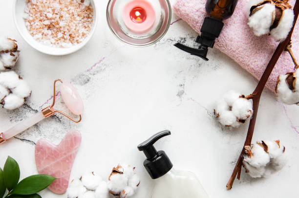 istock Face massage jade roller with cosmetic product on white marble background 1301555154