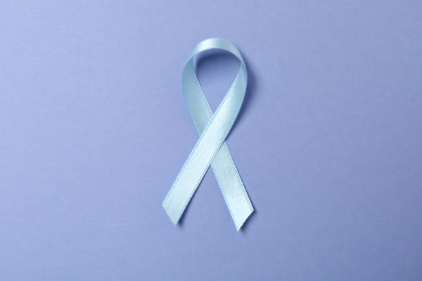 istock Light blue awareness ribbon on light violet background 1301556029