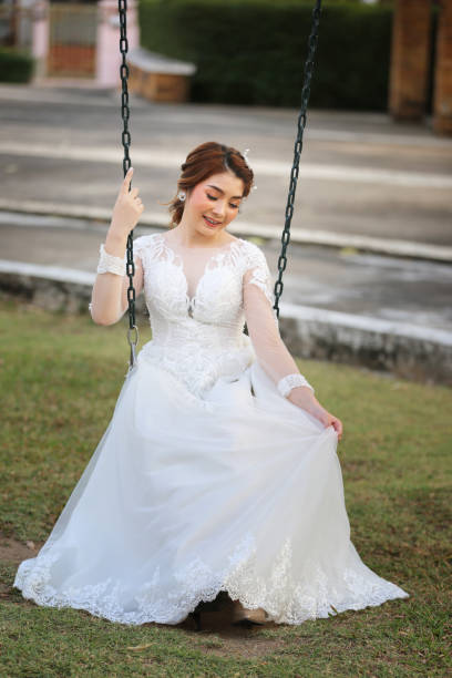 istock Full Length Of Smiling Bride Sitting On Swing 1301564205