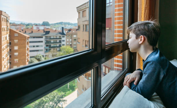 istock Teenager in coronavirus lockdown looking through the window 1301566714