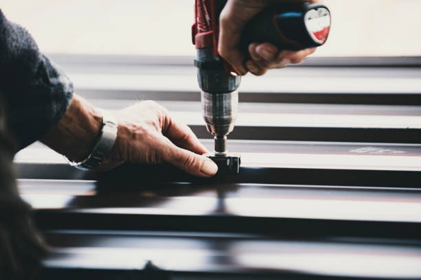 Building contractor is installing metal roofing sheets Building contractor is installing metal roofing sheets on the rooftop of the house using electric screwdriver. metal roofing stock pictures, royalty-free photos & images