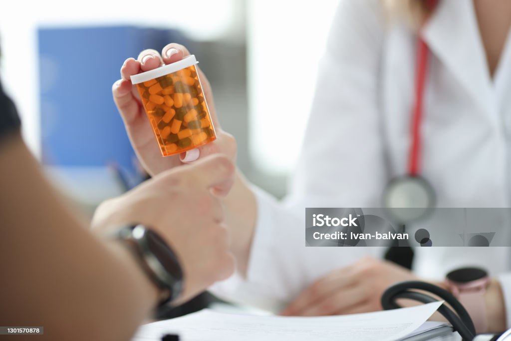 Doctor giving patient jar of medicine in clinic closeup Doctor giving patient jar of medicine in clinic closeup. Pharmaceutical business concept Pharmacy Stock Photo