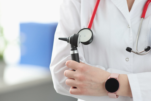 Otorhinolaryngologist holding otoscope in his hands in clinic closeup. Family medicine concept