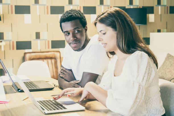 istock Couple of diverse designers sitting at table with laptops 1301571381
